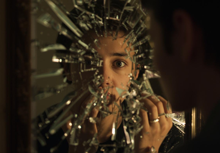 Pessoa olhando para espelho quebrado com reflexo fragmentado simbolizando sonhar com espelho quebrado e conflitos internos